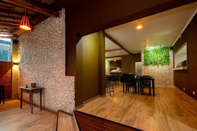 Interior do Noiê Sushi com parede de pedra, iluminação quente e salão ao fundo