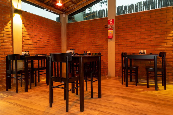 Espaço com paredes de tijolo aparente e mesas para grupos