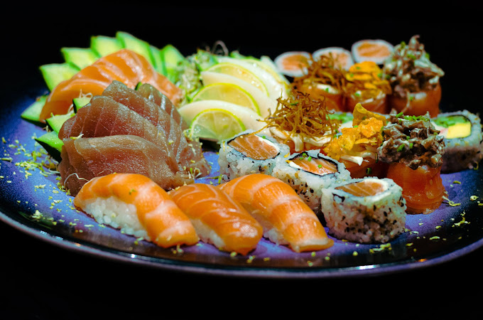 Combinado de sushi e sashimi servido em prato escuro